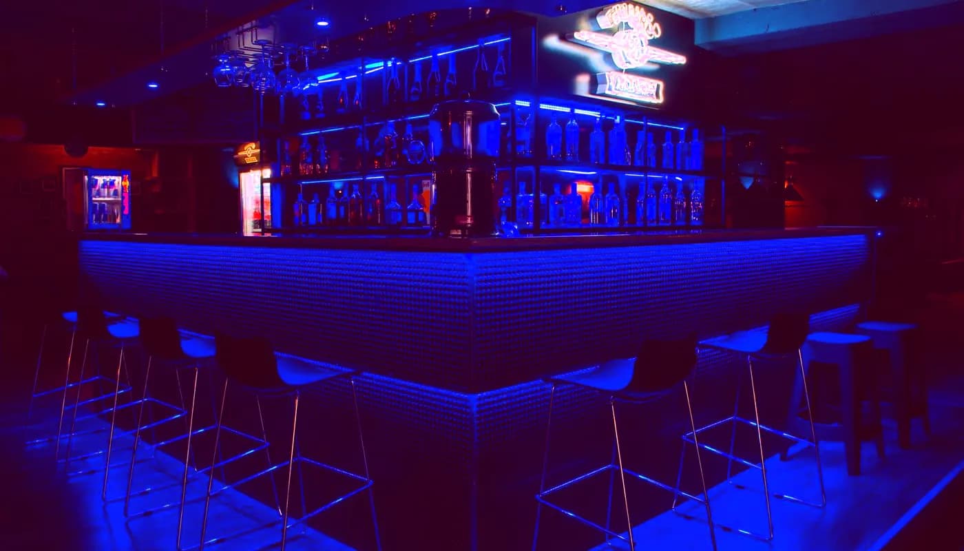 Curved bar counter washed in blue and magenta light