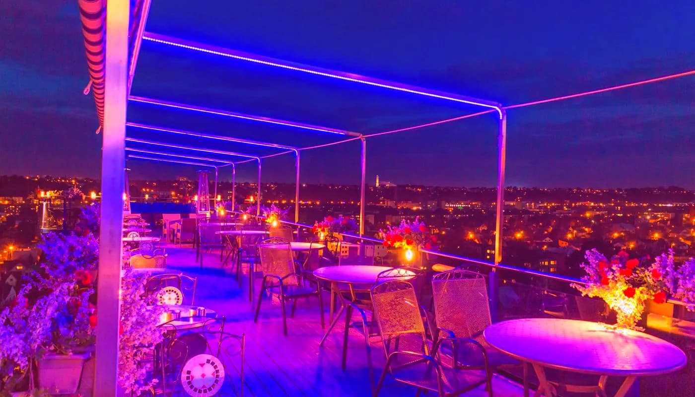 Neon-lit rooftop terrace above city lights at night